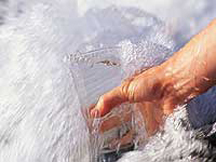 Person filling glass of water from a rush of clear water
